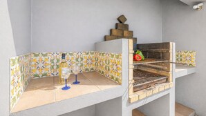 An outdoor grill area with a tiled backsplash and a bottle of white wine. - Villa Dubai (Albufeira)