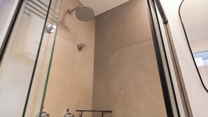 Eine moderne Dusche mit Glastür, Handbrause und Bedienfeld.