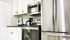 Una cocina moderna con electrodomésticos de acero inoxidable, armarios blancos y un salpicadero con motivo de espiga.