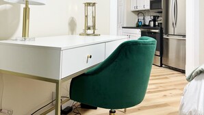 Una cocina moderna con gabinetes blancos, un refrigerador de acero inoxidable y un televisor de pantalla plana montado en la pared.