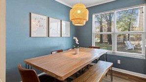 A dining area with a wooden table, benches, and chairs. There is a large window with blinds, and a hanging light fixture. - Vacation home in Tool Kemp, Firepit, Boat Ramp Access 5Min Walk Cedar Creek Lake (Tool)