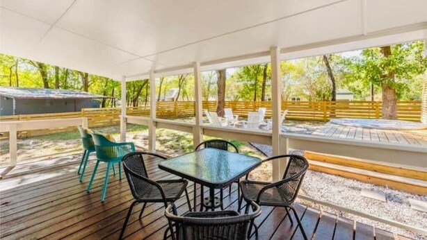 A covered patio area with a table and chairs, surrounded by a wooden deck and a view of trees. - Vacation home in Tool Kemp, Firepit, Boat Ramp Access 5Min Walk Cedar Creek Lake (Tool)