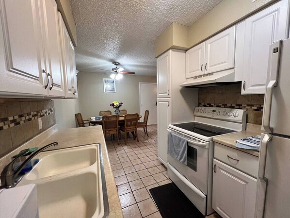 A compact kitchen with white cabinets, a stove, an oven, and a sink. - Lovely 2-bedroom apartment with WiFi, AC in Tucson (Tucson)