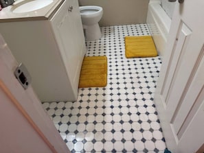 A bathroom with a white and black checkered floor, a white toilet, and a yellow bath mat. - Lovely 2-bedroom apartment with WiFi, AC in Tucson (Tucson)