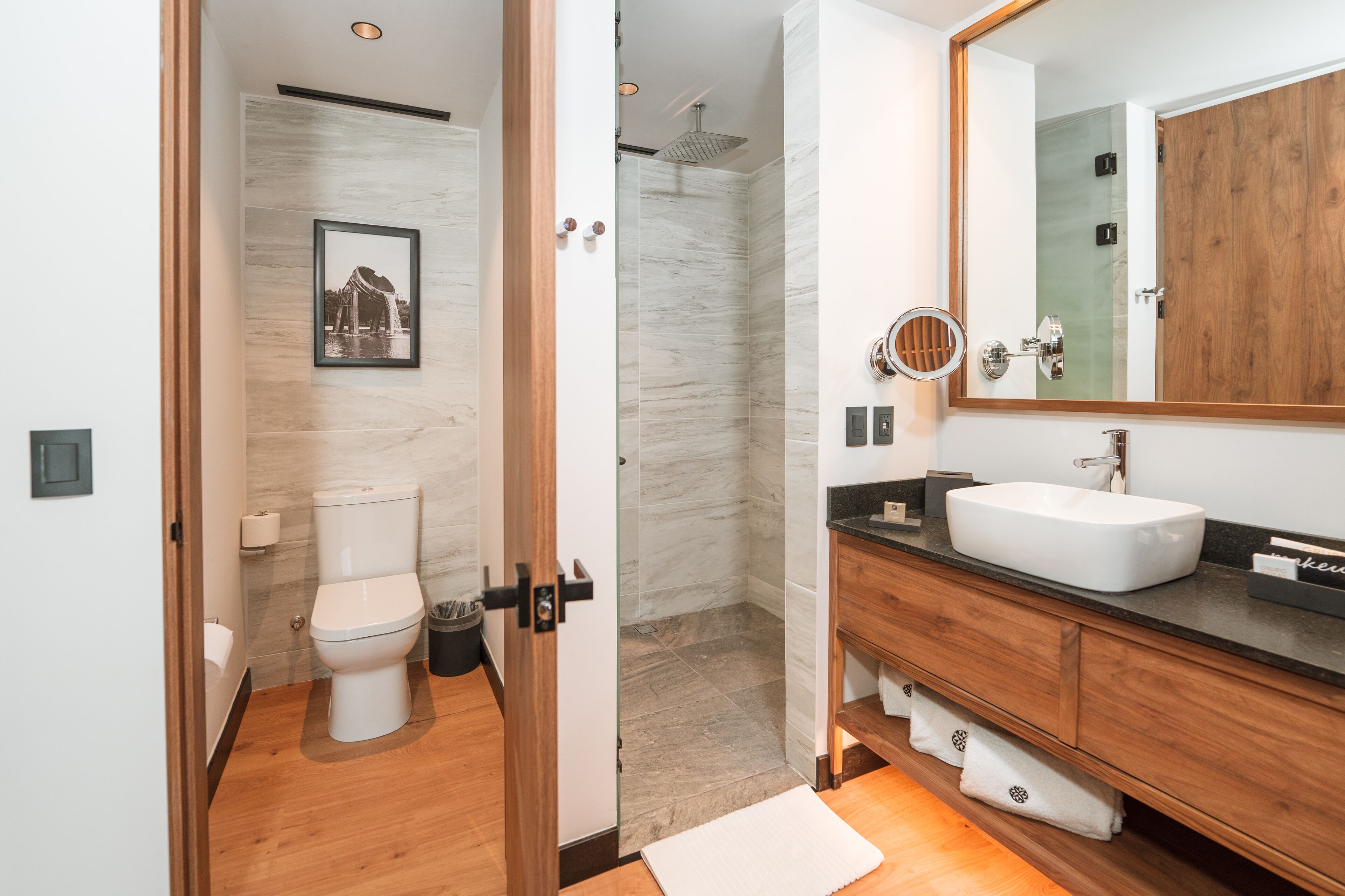 Une salle de bain moderne avec un meuble-lavabo en bois, un lavabo blanc et un grand miroir.