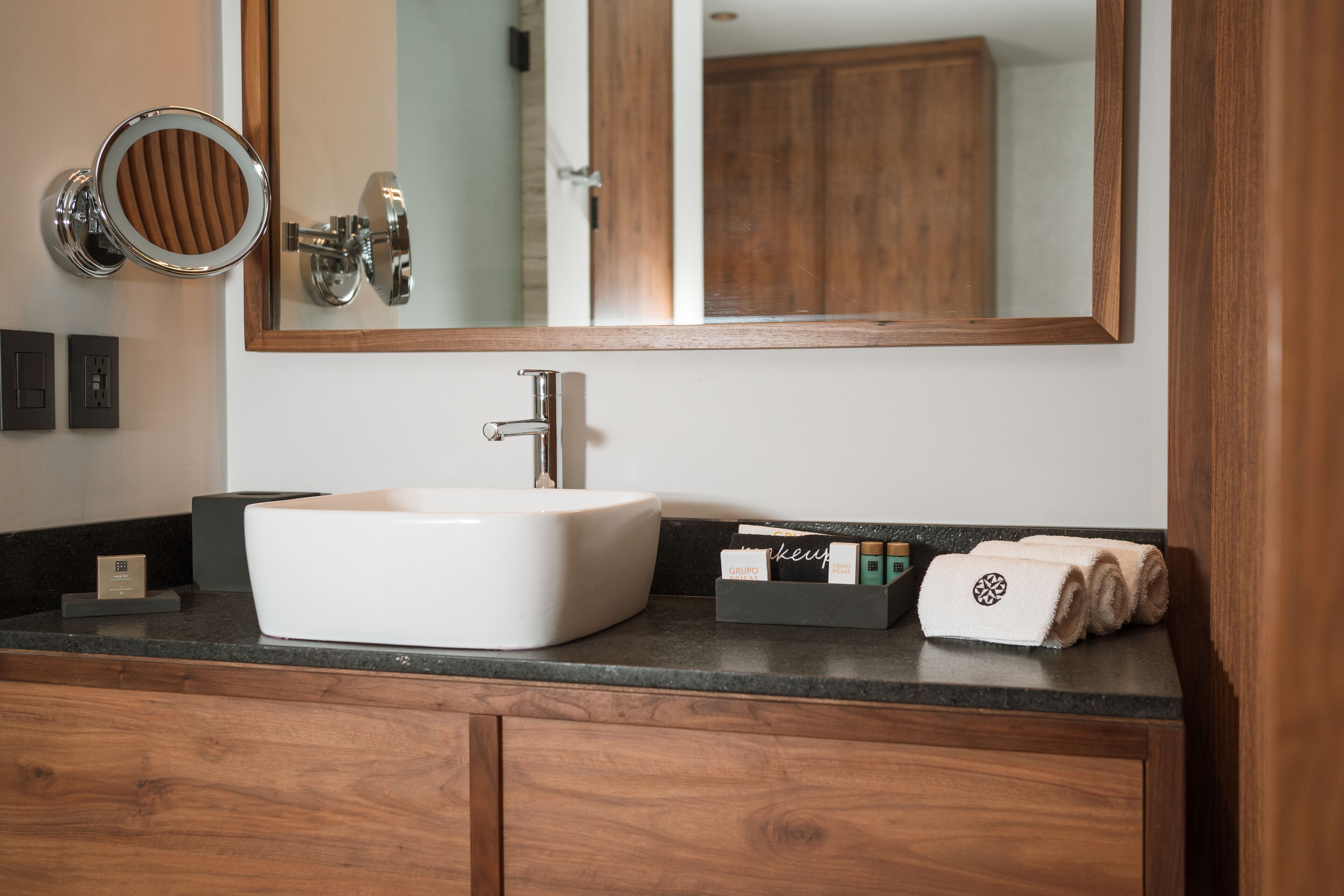 A bathroom with a white sink, a mirror, and wooden cabinets.