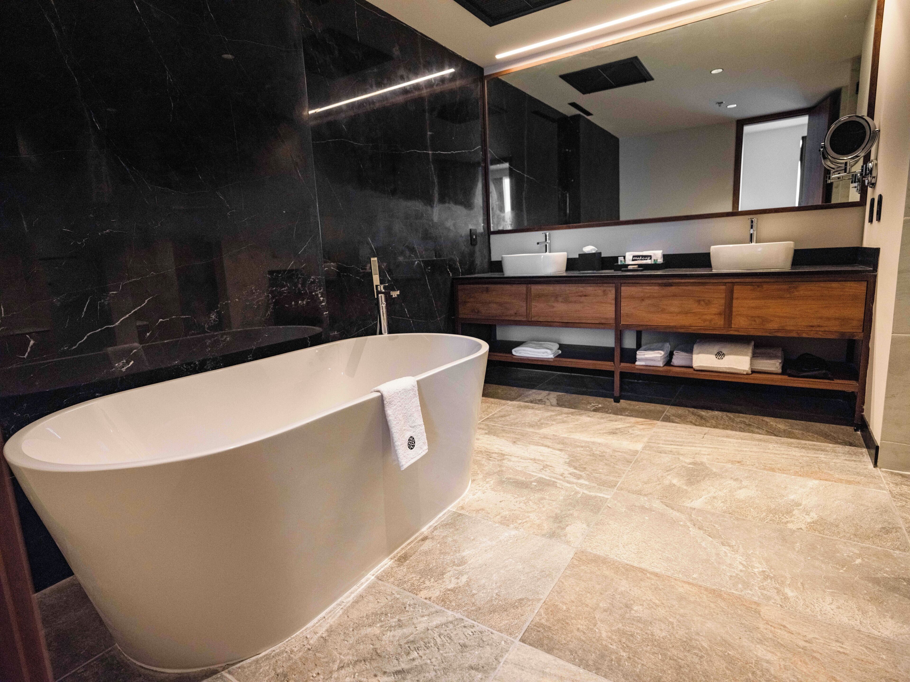 A modern bathroom with a freestanding bathtub, a vanity with a mirror, and a large mirror above the sink.
