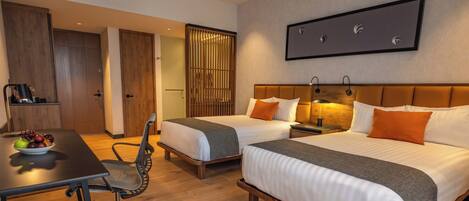 A hotel room with two beds, a desk, a chair, and a dining table.