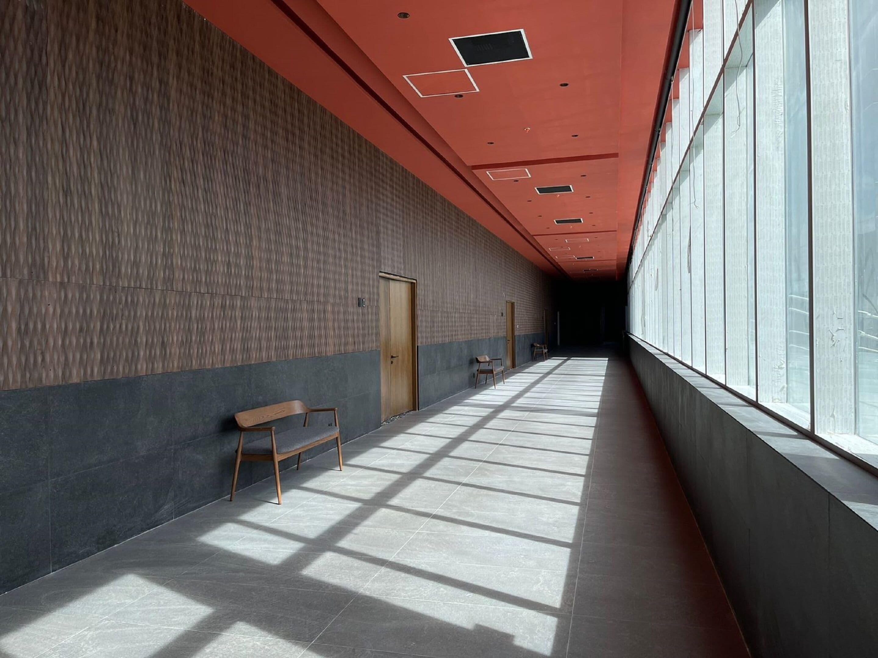 A long, narrow hallway with a bench, a door, and a window on one side.