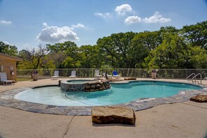 Une piscine avec un jacuzzi, entourée de chaises longues et bordée de pierres.