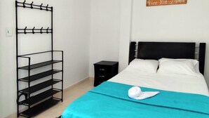 Une chambre à coucher comprenant un lit, une étagère en métal noir, une table de chevet et un panneau décoratif mural.