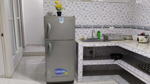 Une cuisine équipée d’un réfrigérateur, d’un évier et d’un plan de travail recouvert de carreaux.