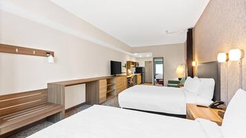 A hotel room with a bed, a desk, a television, and a bathroom visible through an open door.