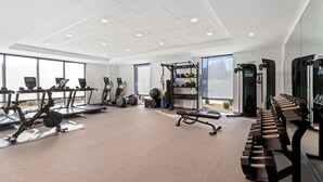 Uma academia moderna com equipamentos de cardio, aparelhos de musculação e um banco.