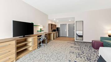 A hotel room with a large bed, a desk with a computer, a television, and a wardrobe.