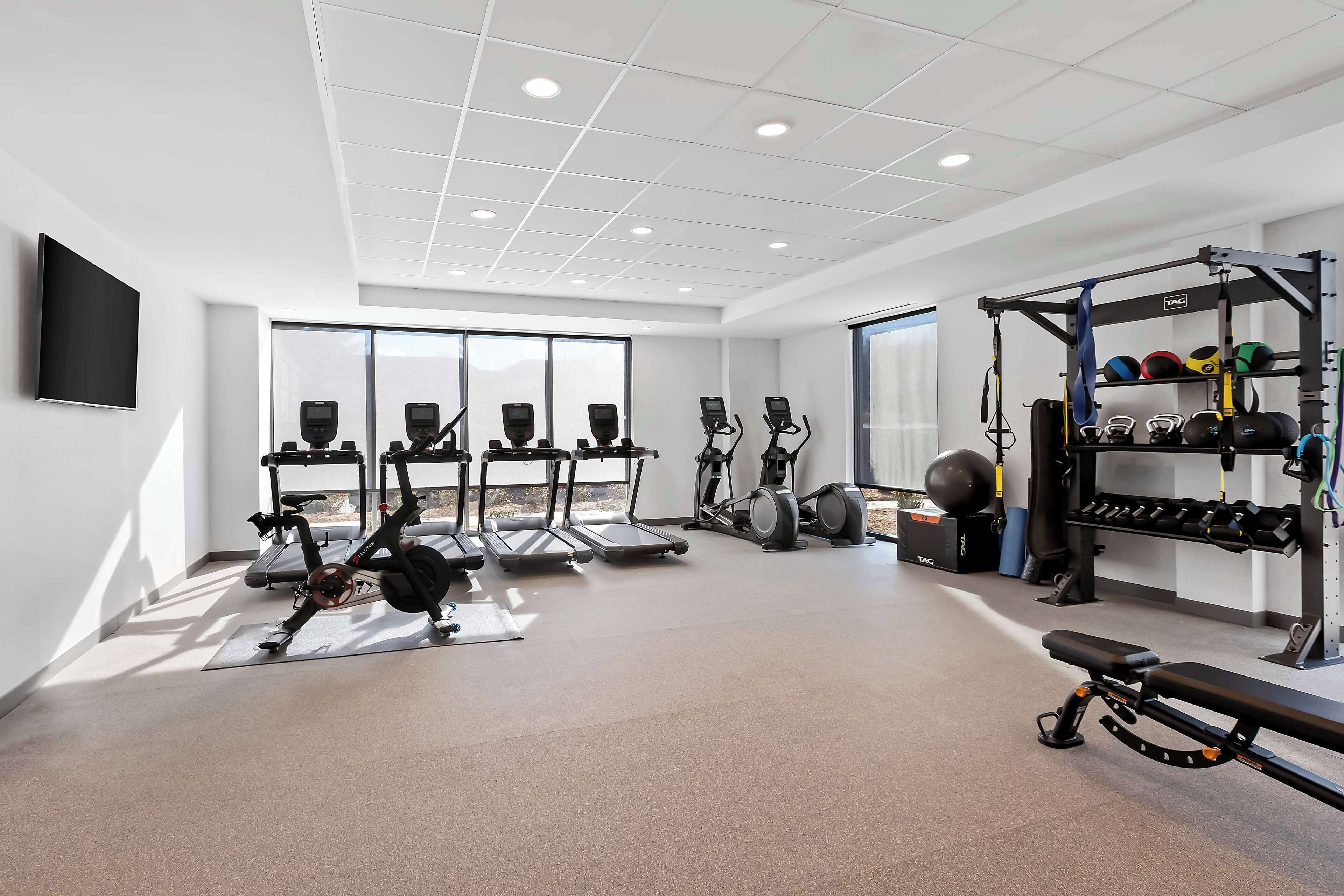 A modern gym with treadmills, stationary bikes, and weightlifting equipment.