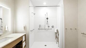 Un baño moderno con ducha a ras de suelo, tocador con espejo y un perchero para toallas.