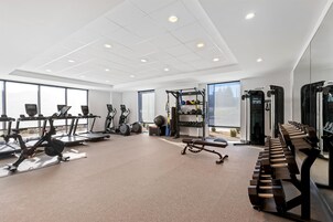 Un gimnasio moderno con cintas de correr, elípticas, pesas libres y una jaula de sentadillas.