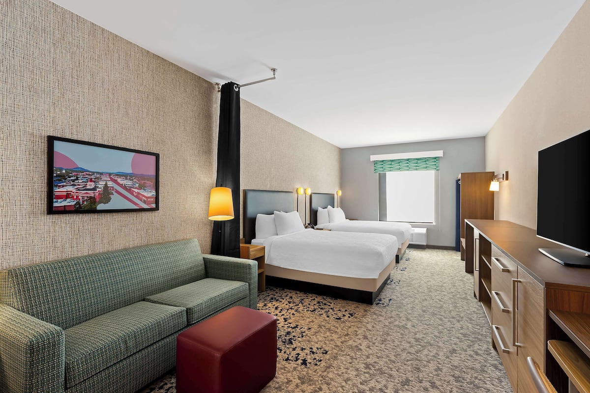 Una habitación de hotel con una cama grande, un sofá, un televisor y un cuadro en la pared.