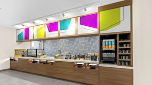 Uma cozinha moderna com armários de madeira, bancada com diversos eletrodomésticos e painel de fundo estampado.