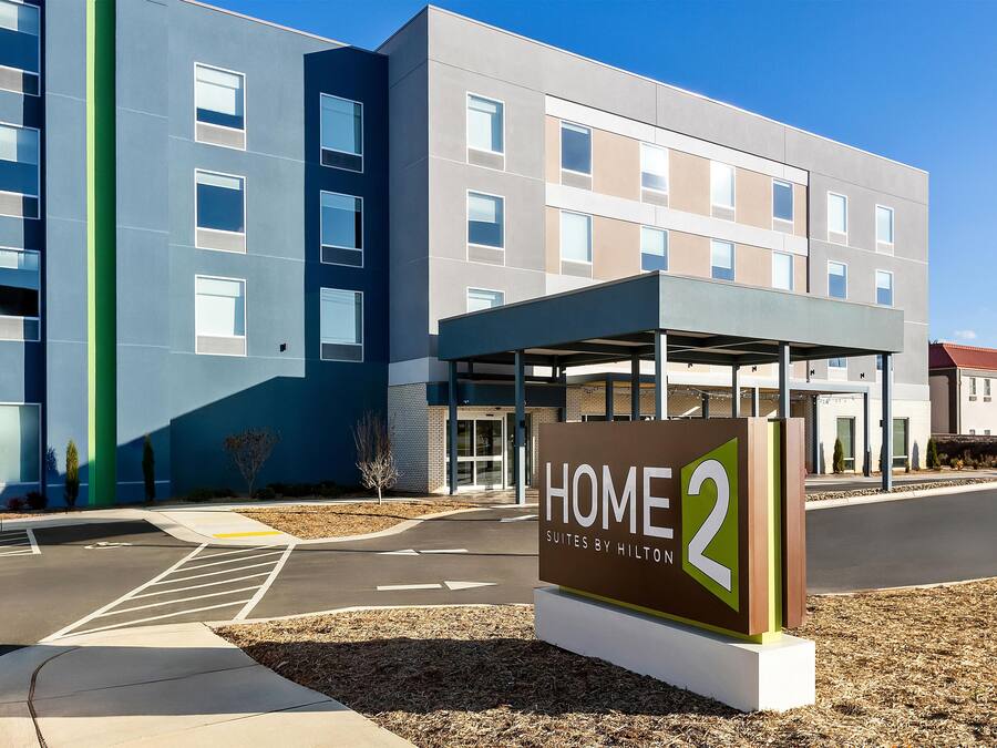A modern hotel entrance with a sign reading 'HOME 2 Suites by Hilton'.