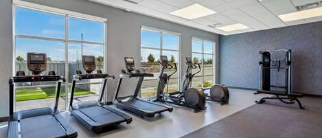 A gym with treadmills, elliptical machines, and a weight bench.