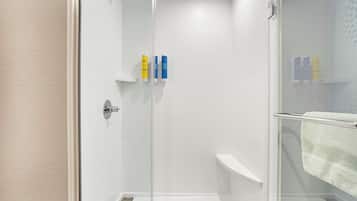 Un área de ducha moderna con puerta de cristal, paredes de azulejos blancos y un perchero para toallas.