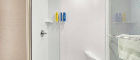 Un área de ducha moderna con puerta de cristal, paredes de azulejos blancos y un perchero para toallas.
