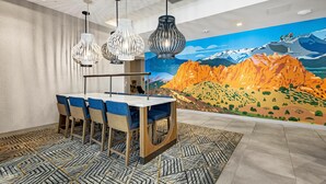 Un comedor con una mesa y sillas, un tapete estampado y un mural con paisaje de montaña en la pared.