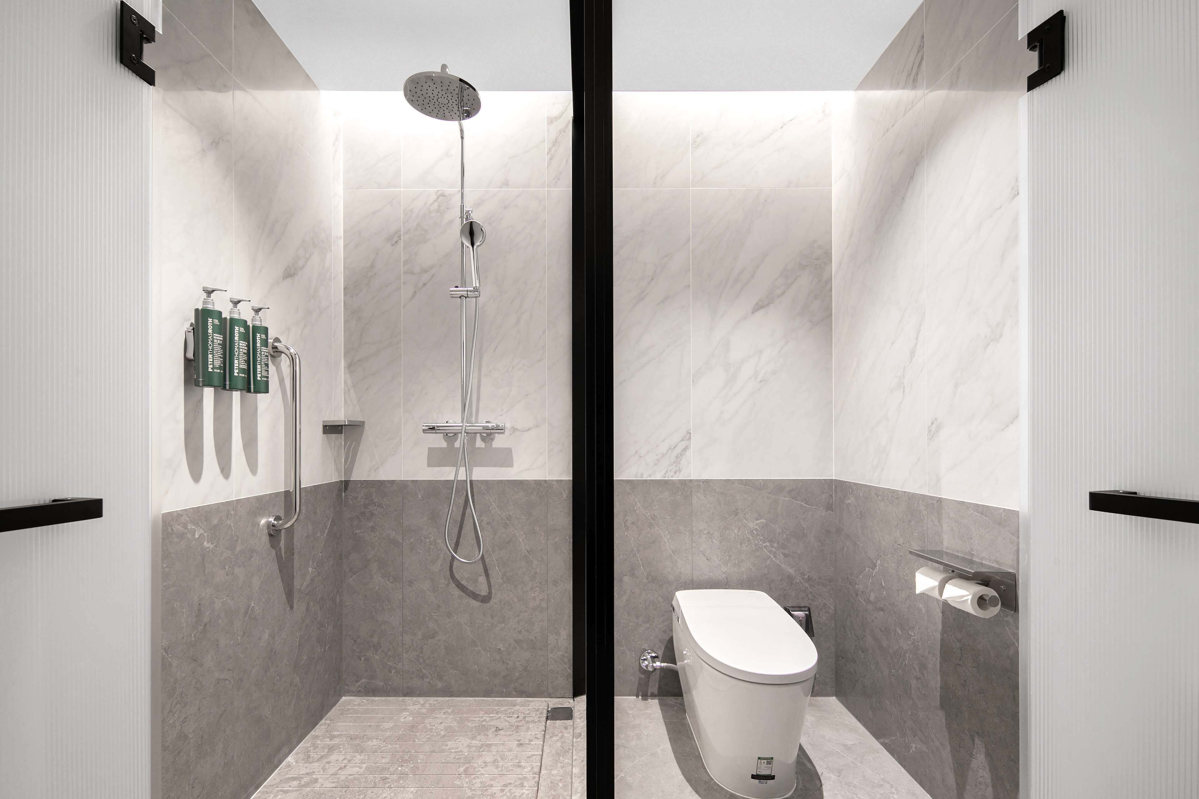 A modern bathroom with a shower, toilet, and towel rack.