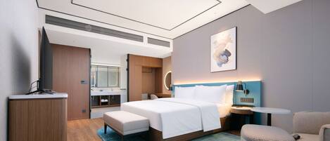 Een moderne hotelkamer met een groot bed, een bureau, een stoel en een klein voetenbankje.