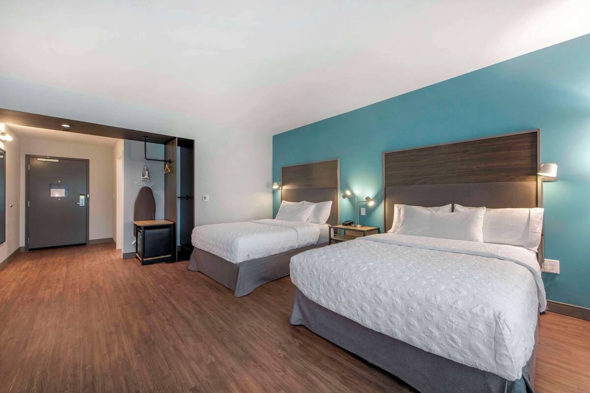 Une chambre d’hôtel avec deux lits, un plancher en bois, des murs de couleur turquoise et un décor moderne.