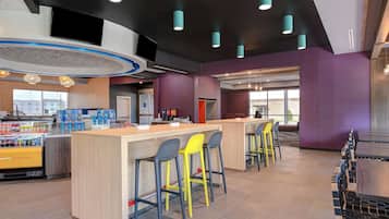 A modern bar area with a central island, bar stools, and a seating area with tables and chairs.
