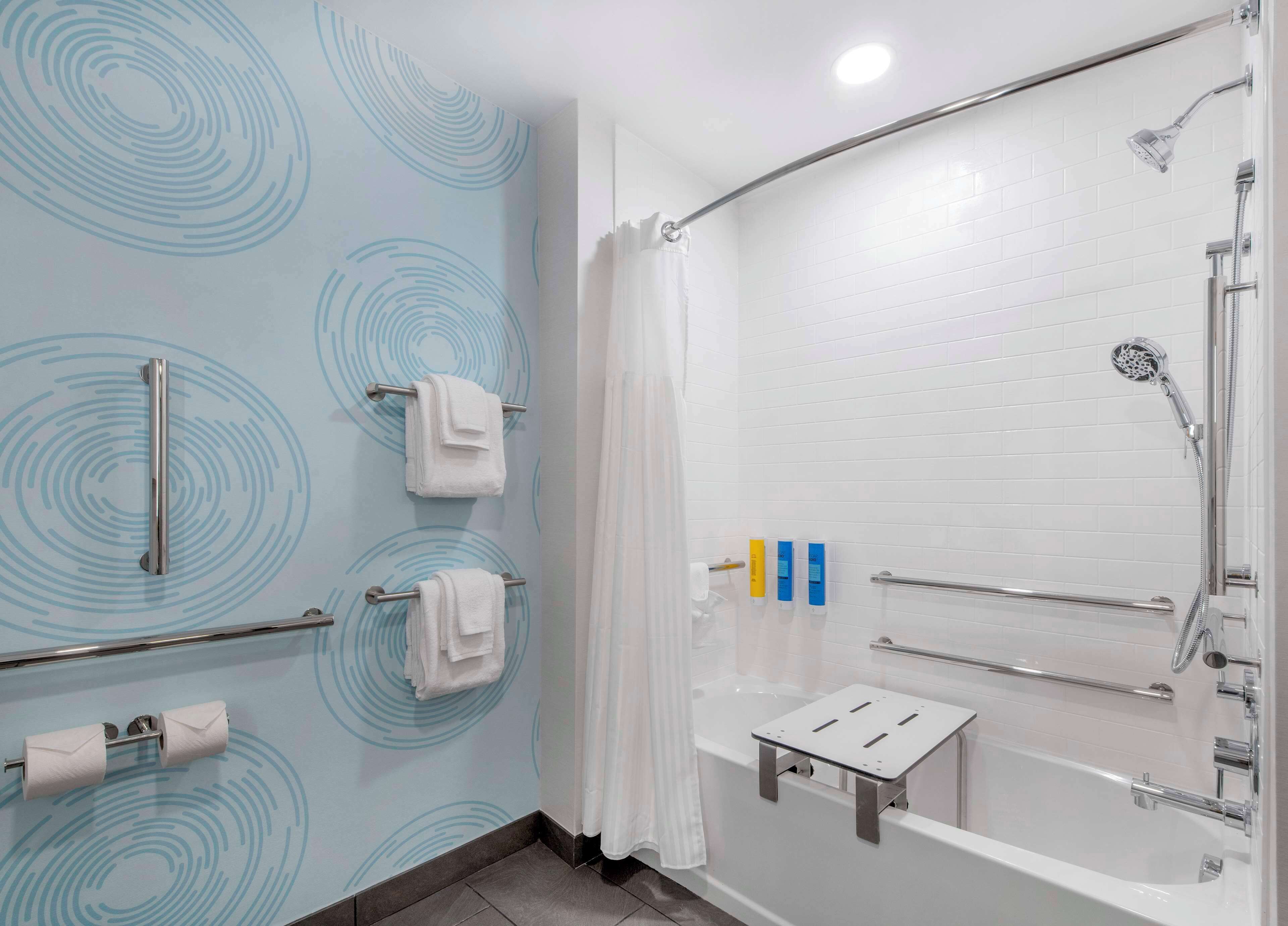 A modern bathroom with a shower, a bathtub, and a toilet paper holder.