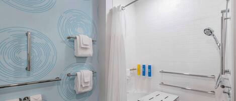 A modern bathroom with a shower, a bathtub, and a toilet paper holder.