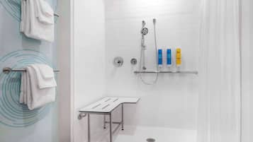 Ein zeitgemäßes Duschbad mit Glastür, Handtuchhalter, Duschkopf und Ablagefläche für Toilettenartikel.