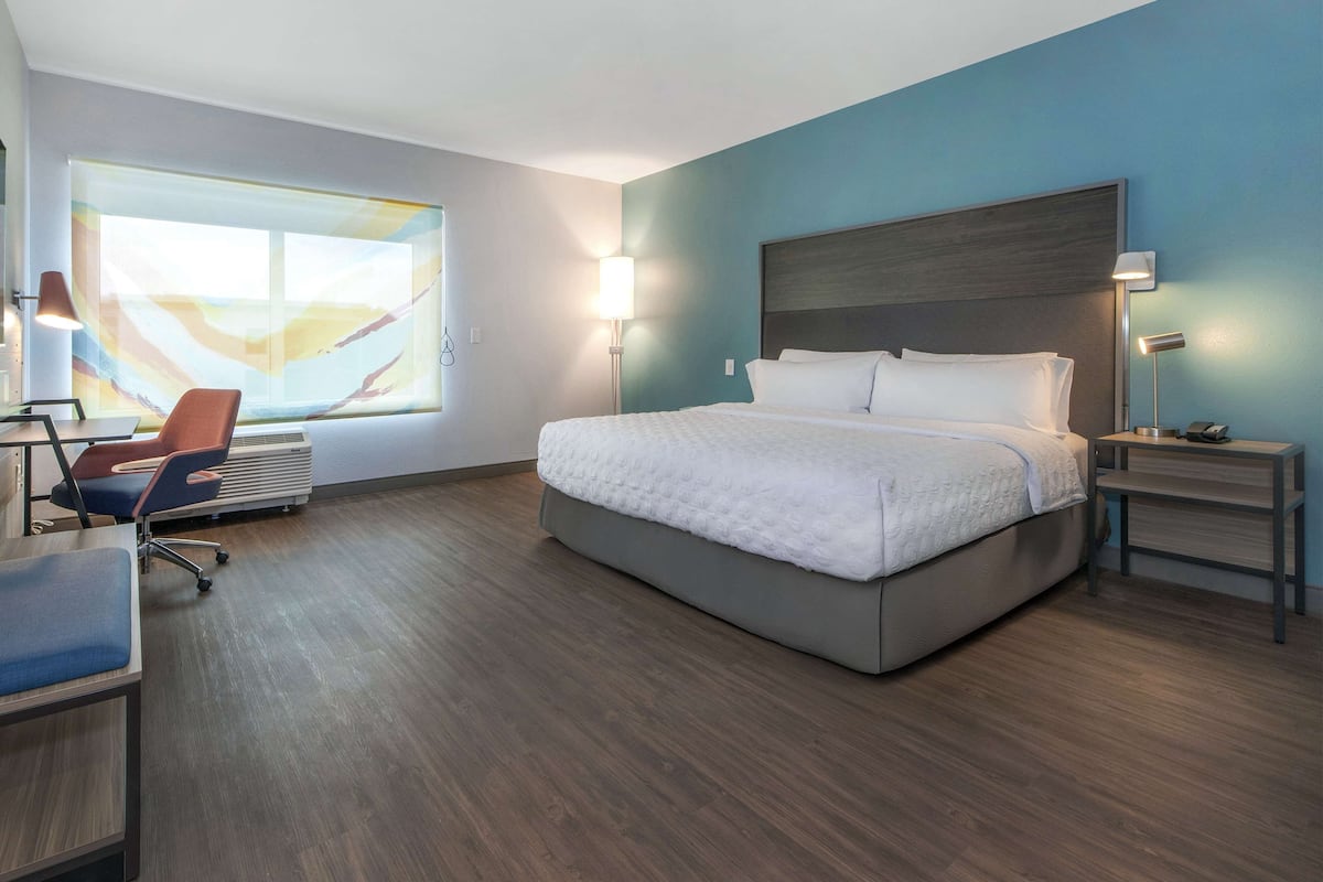 Une chambre d’hôtel moderne, dotée d’un grand lit, d’un bureau et d’une chaise.