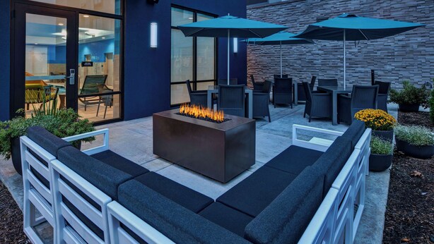 Een terras met zitplaatsen, een vuurplaats, stoelen en parasols.