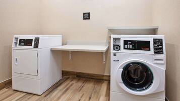 A laundry area with two washing machines and a shelf.