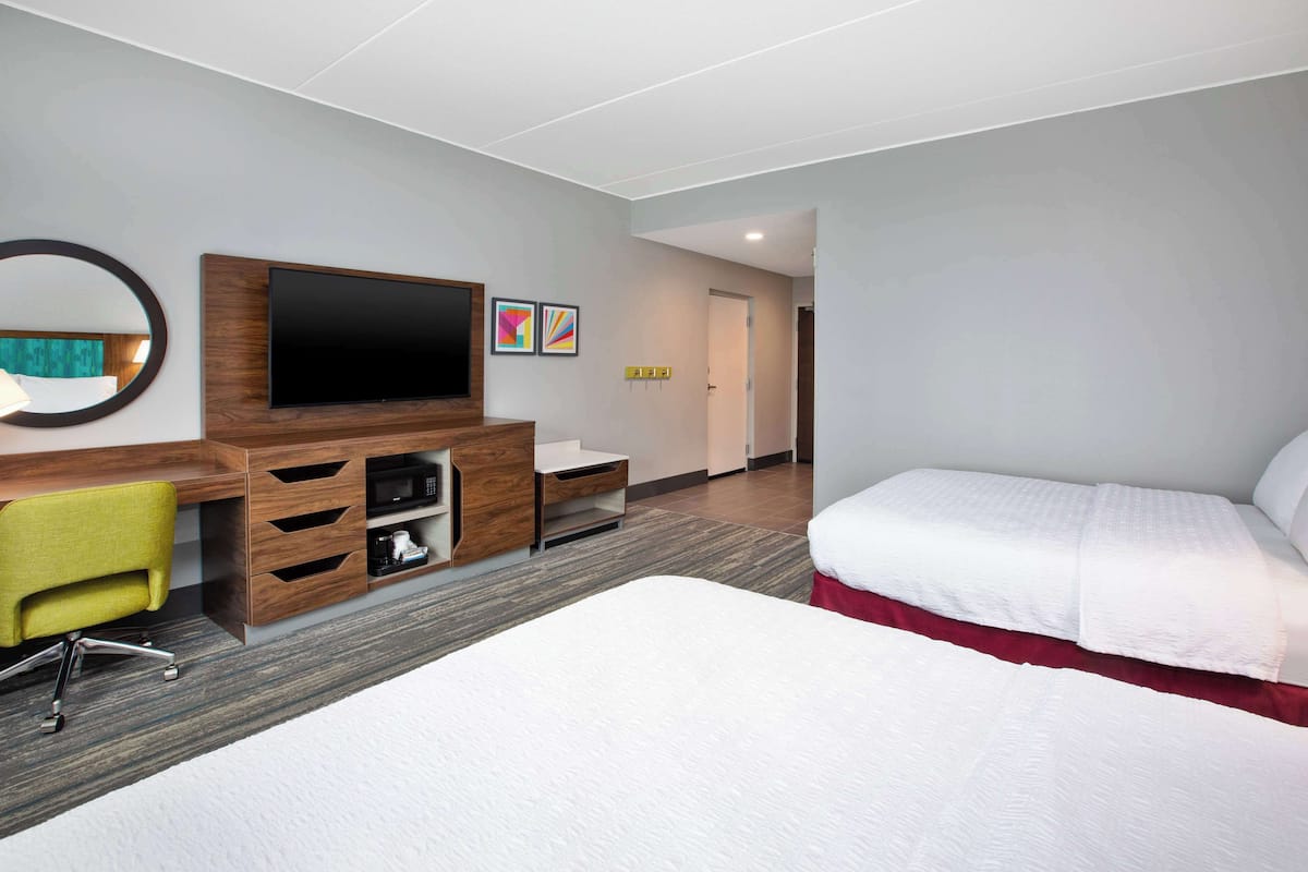 Une chambre d’hôtel avec un lit, un bureau et une chaise, une télévision et des œuvres d’art accrochées au mur.