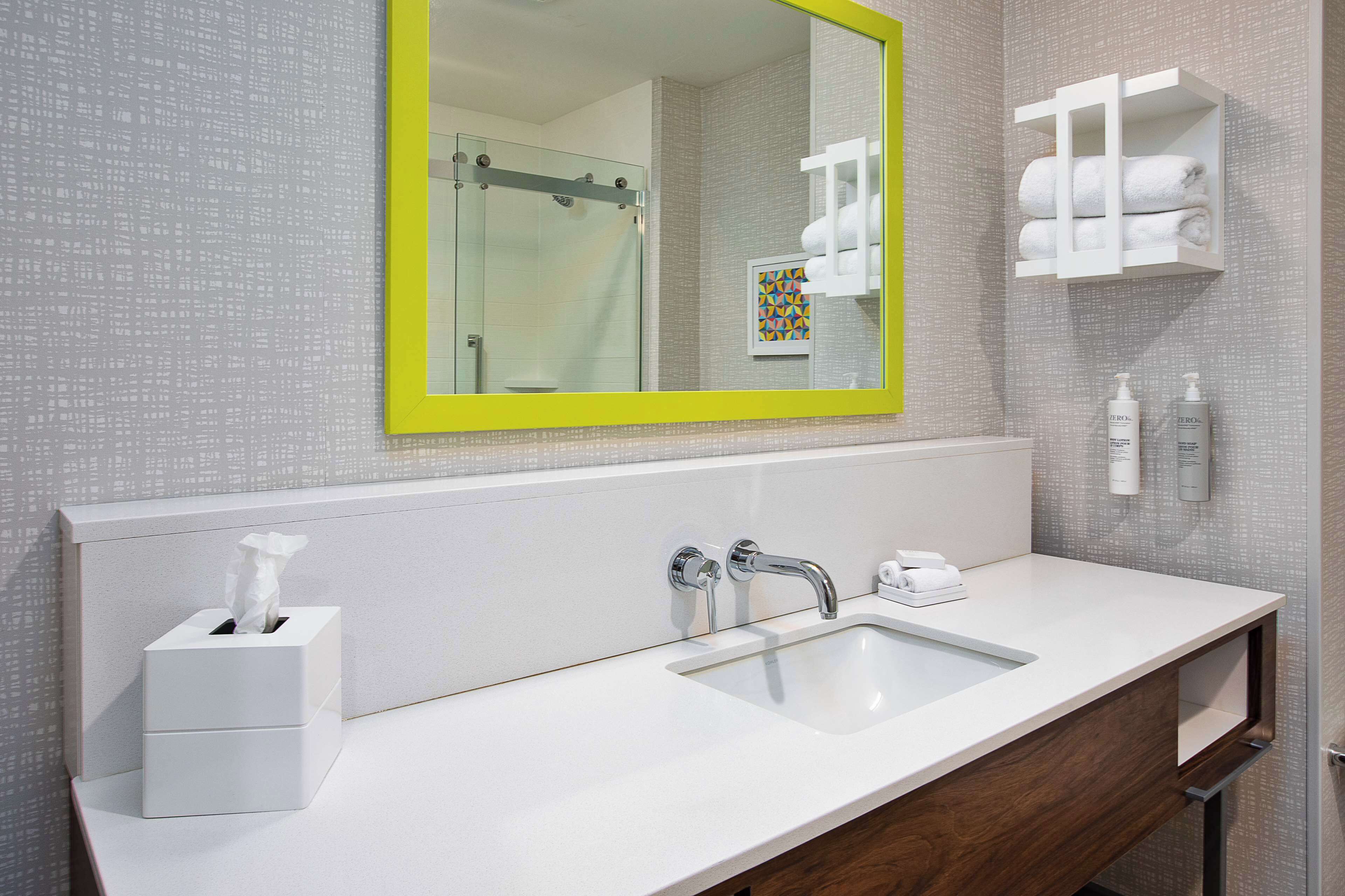 A modern bathroom with a large mirror, a sink, and a shower.