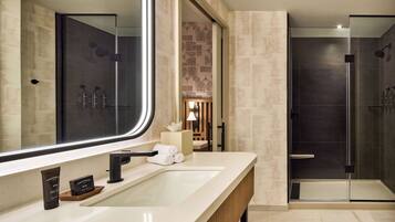 A modern bathroom with a large mirror, a sink, and a shower area.