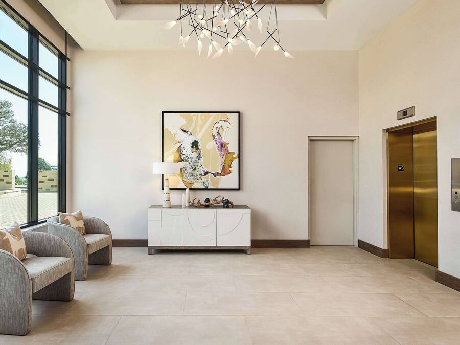 A modern lobby with a large window, a white console table, a colorful abstract painting, and two elevators.