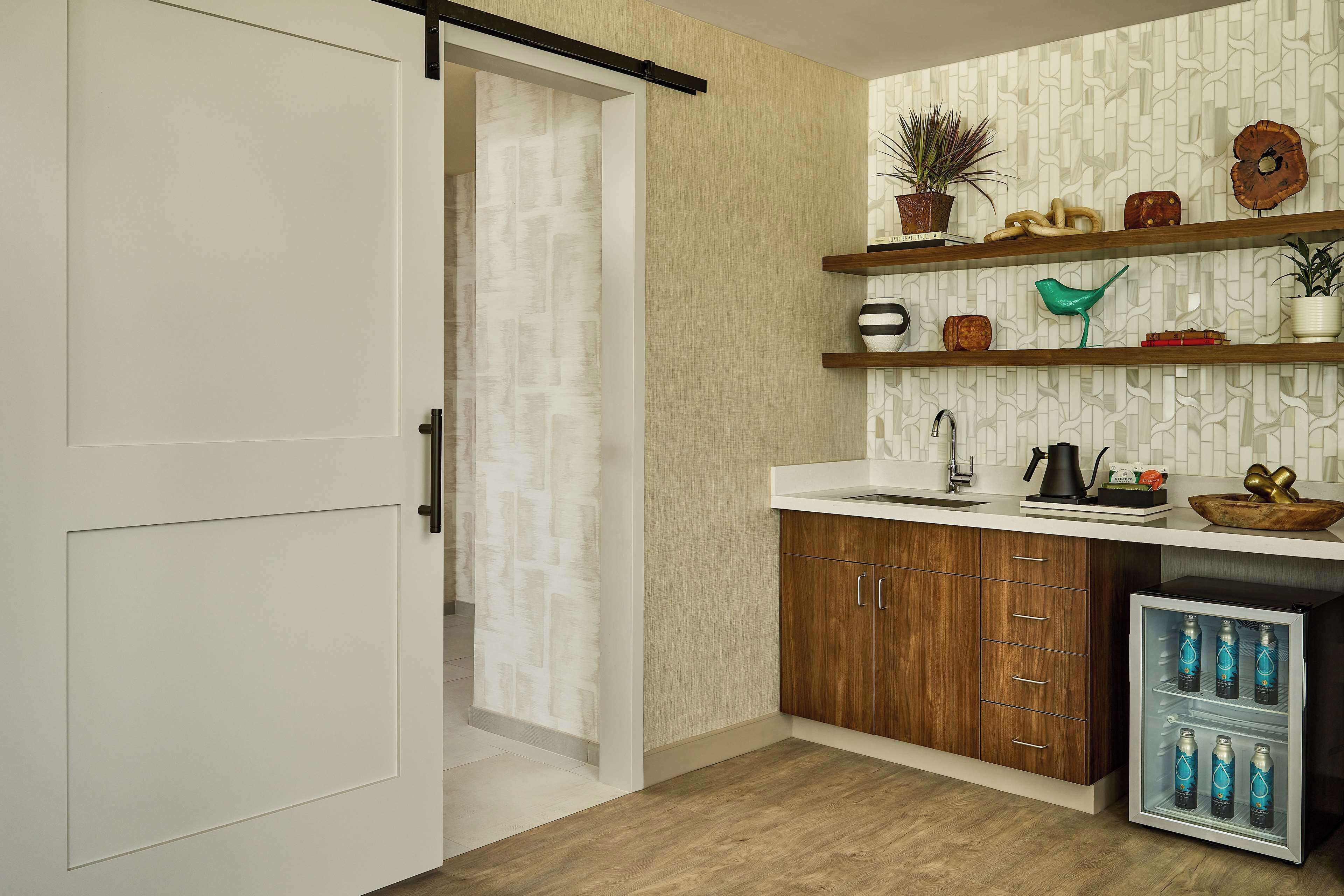 A modern kitchen with wooden cabinets, a built-in sink, and a refrigerator with bottles.