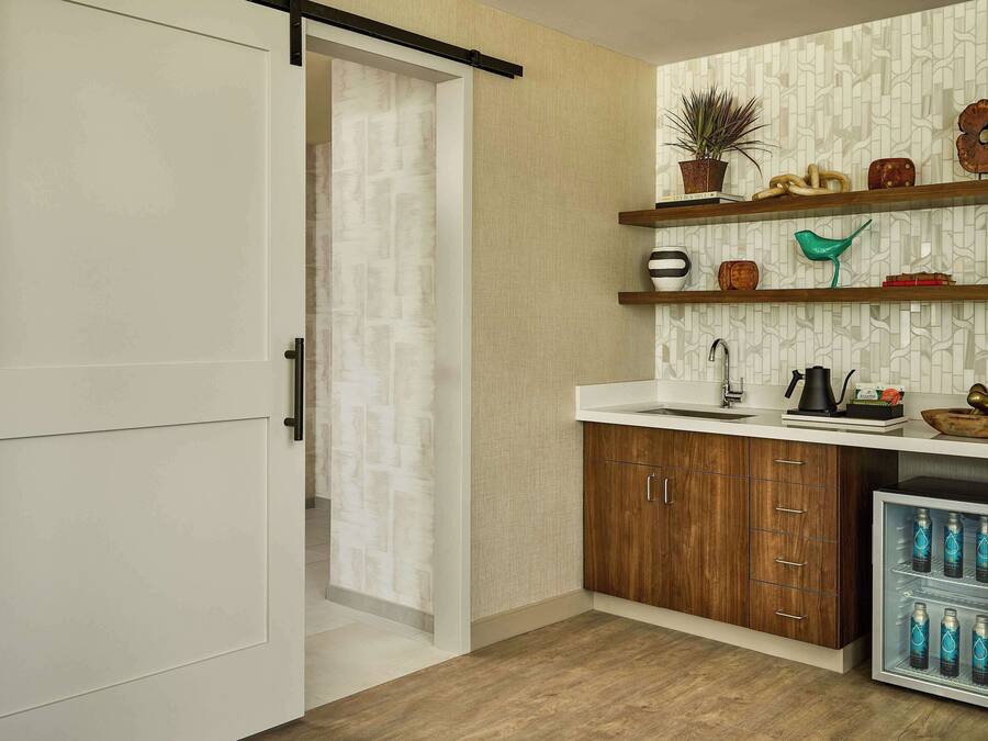 A modern kitchen with wooden cabinets, a built-in sink, and a refrigerator with bottles.