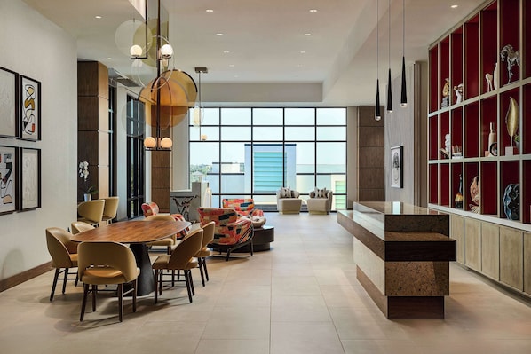 Un comedor amplio con una gran mesa de madera y sillas modernas, una zona de estar con sofás coloridos y un aparador decorativo rojo con varios objetos.