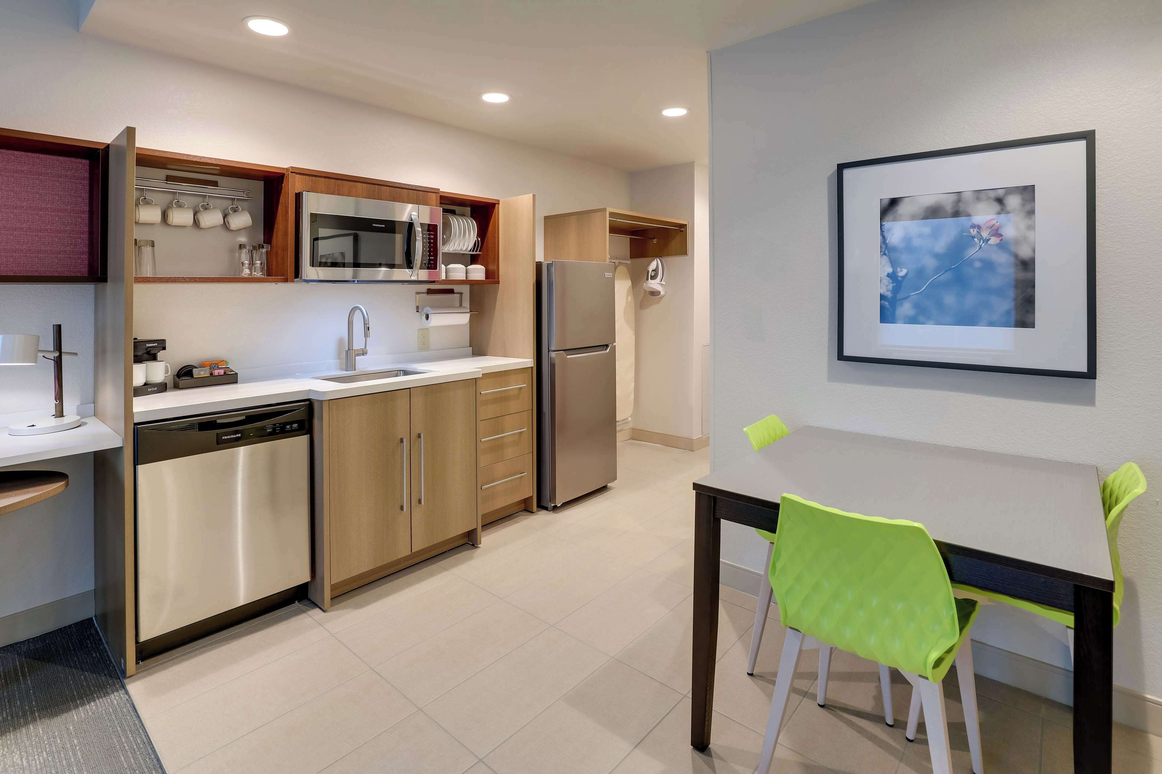 A modern kitchen with stainless steel appliances, wooden cabinets, and a dining area with a table and chairs.