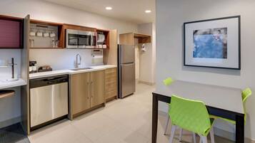 A modern kitchen with stainless steel appliances, wooden cabinets, and a dining area with a table and chairs.
