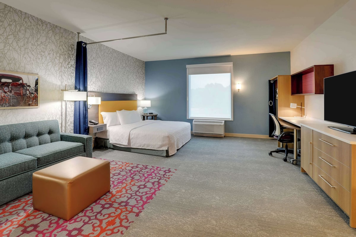 Ett hotellrum med en säng, en soffa, ett skrivbord och en tv.