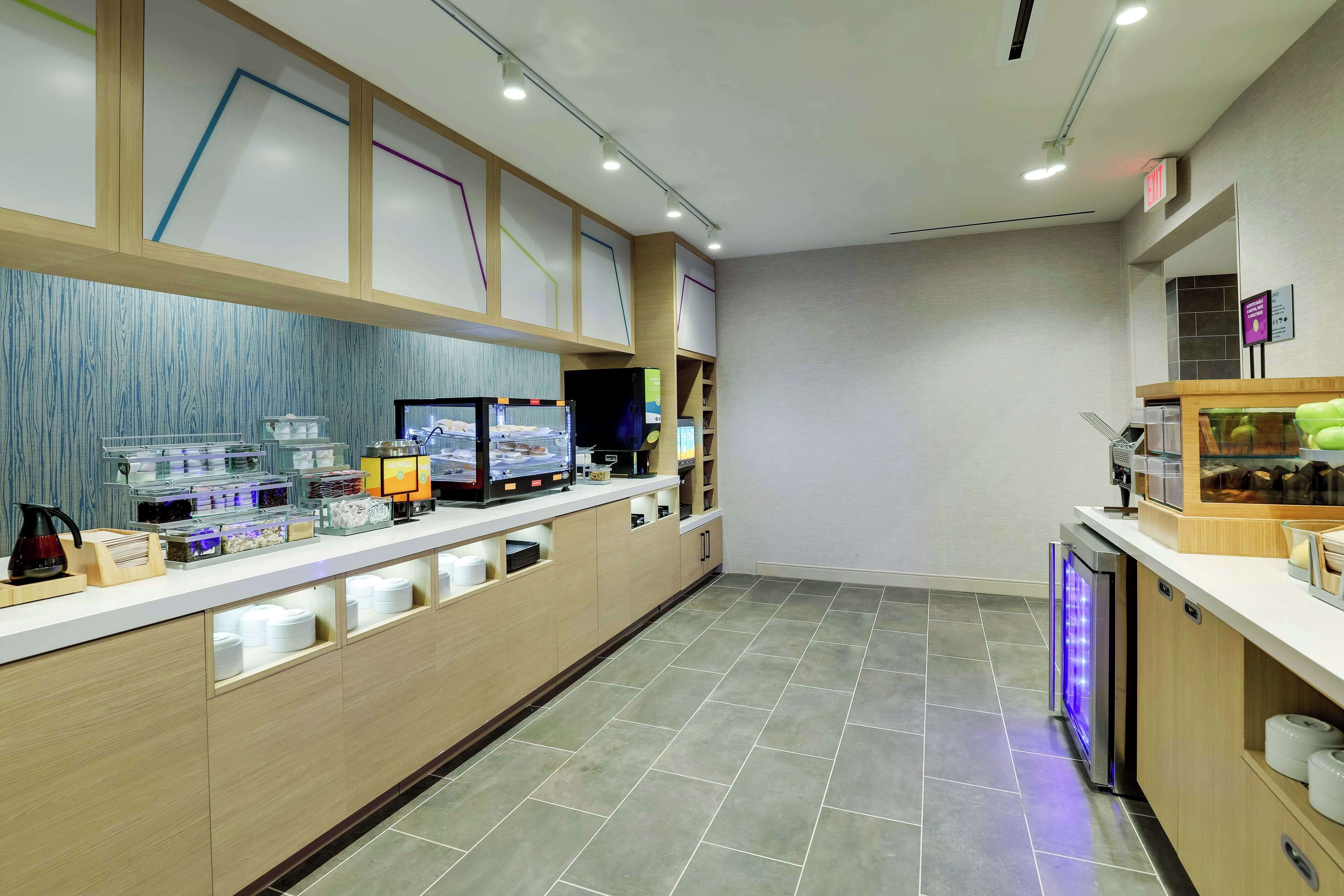 Eine moderne Hotellobby mit einer langen Rezeption, einer Kaffeemaschine und einem kleinen Kühlschrank.